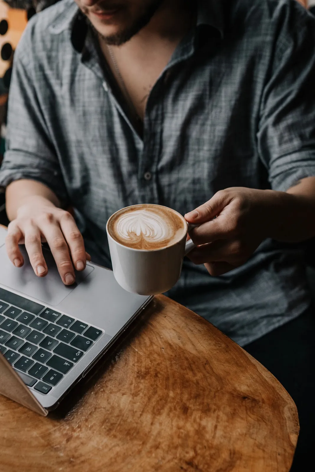 Persona utiliza una computadora junto a una taza de café
