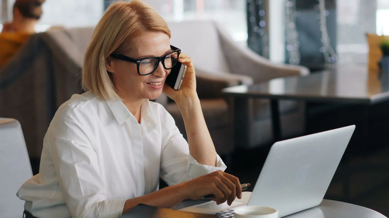 Profesional conversa por teléfono junto a su computadora